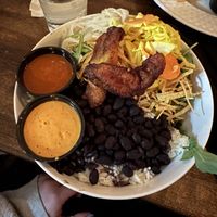 Pow pow pow bowl with curtido, spicy white onions, tortilla strips, and maduros. Side of al pastor sauce and sunflower chipotle sauce.  at Hermanas Kitchen and Cocktails in Lindenhurst