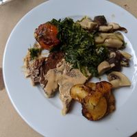 Seitan with gravy, roasted tomato, sauteed greens, mushrooms, and potatoes at GAO in Matosinhos