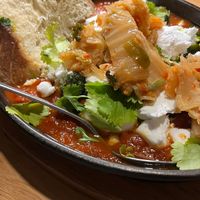 Vegan shakshuka with cilantro, champignons, feta and focaccia, + extra kimchi. at Kolm Tilli in Tartu