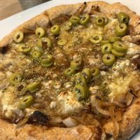 Pizza vegana con harina integral , queso vegano , aceitunas y cebolla caramelizada   at Kinoa in Malaga