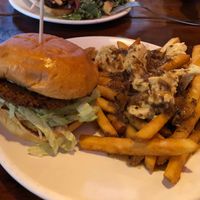 Spicy Seitan Sandwich with poutine! Nashville style fried seitan patty, bread and butter pickles, lettuce, and sriracha mayo on a potato bun. at Bad Apple  in Vancouver