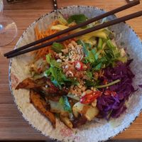 Flavorful noodle bowl with many vegetables, herbs and "duck", and noodles and sauce at the bottom. at Well Being in Cologne
