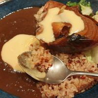 Curry with brown rice, half a roasted onion and melty vegan cheese at RUCY+R 横浜ジョイナス店 in Yokohama