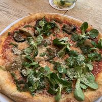 ‘The garden’ tomato sauce, homemade cheese, grilled zucchini, artichoke, lamb lettuce, homemade Parmesan and salsa verde  at Vegan Pizza Bar in Rotterdam