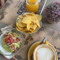 Nachos con guacamole y pico de gallo para picar, zumo de naranja y café con leche de avena at Rawcoco in Mallorca