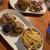 Hot honey chicken biscuits and cheese fries (front), campfire burger with breakfast potatoes (back)  at Brunch Bird in Austin