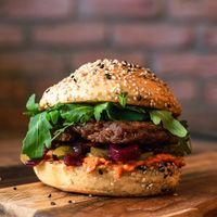 Vegan Burger made from Seitan & Jackfruit, Ajvar / Paprika Chutney, Onion jam, Pickles and lettuce topped with vegan brbq spicy sauce or garlic sauce. at Fjaka in Amsterdam
