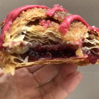 Layers and layers of flaky pastry sprinkled with sugar and featuring a touch of berry frosting which hide a big pocket of raspberry filling  at SPLIT Bakehouse in La Mesa