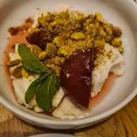 Krem sernikowy z wanilią i pistacjami, śliwki gotowane w wermucie, limonka, mięta at Peaches Gastro Girls in Warsaw