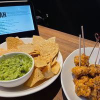 Guacamole and chips. Whiskey pepper Gardein wings. Wings half eatin and guacamole seasoned at the table. at Yard House in Sacramento
