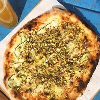 Vegan pizza topped with oat-based cream, vegan cheese, courgette and pistachios at Far i hatten in Malmo