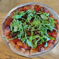 Make your own pizza with arugula, vegan sausage, and grilled onions at Pinthouse Pizza in Austin