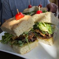 Badass vegan sammy in foreground, breaky-wich in background and lattes with oat milk on the side.   at The Roxy Cafe in Vernon
