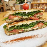 Vegan mafia sandwich with focaccia bread, filled with melted vegan cheese, lots of spinach, some pesto and fresh tomatoes at Nibs Healthy Bar in Menorca