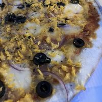 Pizza con Vuna, queso vegetal, aceitunas negras y cebolla  at Super Vegan in Barcelona