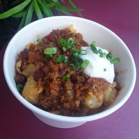 Plant-based Totchos - "Chili", "Cheese", Green Onions, & Corn Chips over Potato Barrels at Walt Disney World - Woody's Lunch Box in Lake Buena Vista