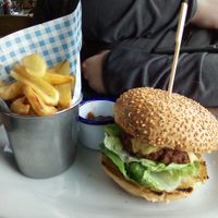 Vegan burger and chips. Contains mock meat style patty and vegan cheese. Had a decent meaty texture if you like that kind of thing. Chips are cut in a weird way so they're curved. at Perch on Lancing Beach in Lancing
