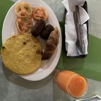 Desayuno- arepa, tomatoes, sausages, sweet bread and juice for 6000 COP  at El Enebro in Pereira