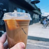 Exterior of building, takeaway container with an iced dirty chai with oat milk. at Elegy Coffee in Nashville
