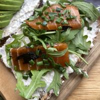 A slice of multi grain seed bread with white bean feta spread, rocket and marinated salmon  at Froindlichst in Berlin