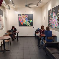 Indoor seating with multiple tables and a small couch. Local art on the walls for sale. at Kilovolt Coffee in Oakland