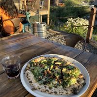 Pesto pizza with vegan cheese and glass of wine.   at Crosscut Pizzeria and Taphouse in Nederland