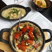 “Kabsé, riso con verdure cotte, cardamomo.
mandorle e salsa rossa” in the front, delicious hummus in the back on the right, some rice on the left  at Dukka in Brescia