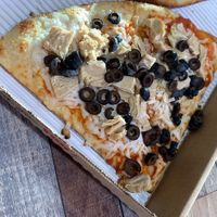 Two vegan pizza slices with vegan chicken, black olives, and vegan cheese at University Pizza Company in Riverside