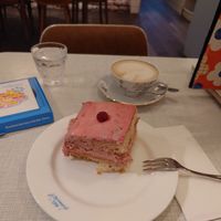 Gigantic piece of raspberry cake and cappuccino with oat milk at Vollpension in Vienna