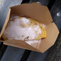 Inside the box, a large pancake covered in icing, with biscoff oozing out the middle. at Scoops in Caernarfon