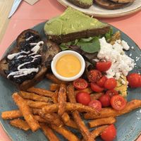 Vegan brunch plate: chickpea omelette, feta cheese and cherry tomatoes / avocado toast and sweet potato fries with harissa mayo / banana bread with coconut yogurt and blueberry jam at Shake Café in Florence