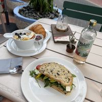 Croissant with jam, avocado smoothie bowl, vegan love sandwich on olive bread, dirty chai latte with oat milk, botanical soda - floral fizz   at Cafe Bonchi in Willemstad