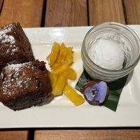 Slightly crisp crusty banana cake in cream, caramelized pineapple, a superrich little chocolate ganache bomb with edible purple flower, and macadamia ice cream  at Beach House by Roy Yamaguchi in Kahuku