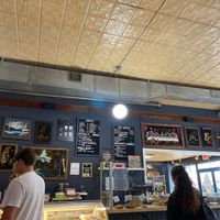 Counter with menu (showing vegan breakfast sandwich and plant milk beverage options) and pastry case (including vegan pastries) at Crumb Bum in Littleton