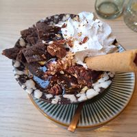 Chocolate Caramel Cookie Sundae — Creamy Oatly® soft serve with chocolate chip cookie, caramel swirl, whipped cream, and caramelized pecans at Copper Branch in Utrecht