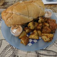 Crab cake poboy with side of potatoes at Meals From The Heart Cafe in New Orleans