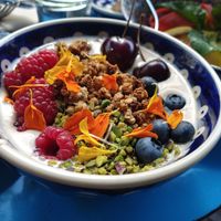 Amandelyoghurt met granola, pistache, vers fruit en eetbare bloemen at DAR Restaurant & Cocktail Bar in Zurich