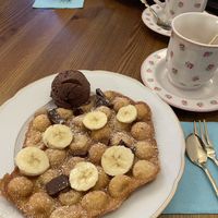 Waffle with banana, chocolate ice cream and chocolate pieces. Cappuccino with oat milk   at Waffelwerker in Lohr