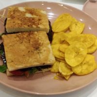 Vegan Reuben Sandwich with fried plantain: Vegan Pastrami, arugula, pickled onion, bell pepper dressing in focaccia bread

 at Kitchen in Panama City