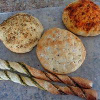 3 Mini Focaccias in Tuscan Seasoning, Sea Salt, and Fresh Herbs and Aleppo Pepper and 2 Pesto Breadsticks. Great sizes for slicing and sharing. Available g/f. at Evexia in Aurora