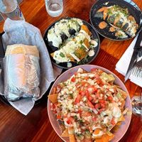 tres hermanas burrito (left); nachos (bottom); corn empanada (middle blue corn), soyrizo empanada (middle yellow corn), and tres hermanas empanada (top) at Mis Tacones in Portland
