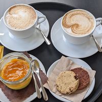 Two cappuccinos, mango cheesecake pot, cookie dough biscuit and another biscuit at Cortese Café 900 in Florence