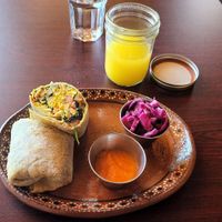 Pineapple Lemon Ginger juice, breakfast burrito, Habanero Carrot hot sauce, pickled cabbage at Soluna Cafe in Jackson