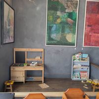 Art for sale on walls, and kids play area with lots of high chairs at Bluebird Bakery in York