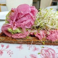Savory waffle with beetroot hummus, avocado, sprouts, pickled red onion, and chili sesame at Oslo Raw Frogner in Oslo