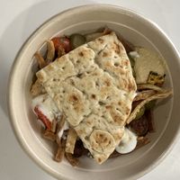 Bowl with white rice, hummus, falafel, corn, tomato and onion, pickles, pita chips, garlic dressing, tahini Caesar dressing, free pita  at CAVA in Melville