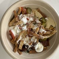 Bowl with white rice, hummus, falafel, corn, tomato and onion, pickles, pita chips, garlic dressing, tahini Caesar dressing  at CAVA in Melville