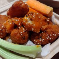 Buffalo cauliflower wings with side ranch. More wings w different sauce underneath paper. at elephant + vine  in Evanston