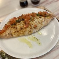 Mittagsmenü, Pizza nach Wahl Pizza Principessa, gefüllt mit Grillgemüse und veganem Käse. Oben drauf Tomatenwürfel mit Zwiebeln, Basilikum und Olivenöl.  at Uno e più in Kriens