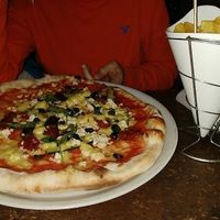 Papas fritas y pizza con aceitunas negras, calabacín, queso y tomate seco at Sfizy Veg in Berlin